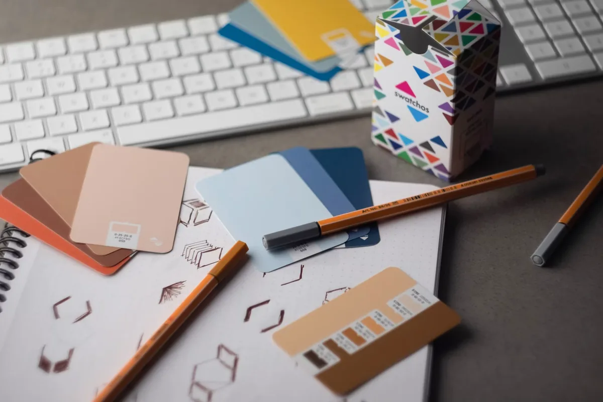 Color swatches and pens beside logo sketches on a designer’s desk