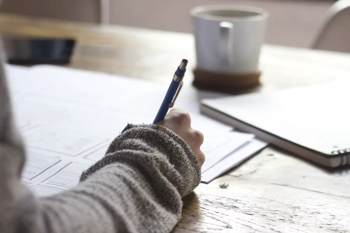 Writing plans on paper at a wooden table