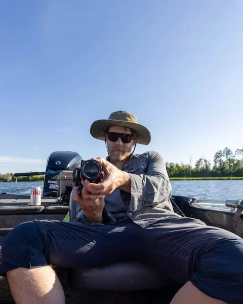 Photographer holding a stills camera on a boat during an outdoor shoot.